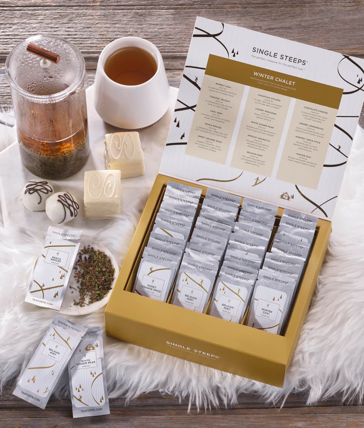 Winter Chalet Single Steeps Tea Chest open with loose tea pouches, a cup of tea and tea press