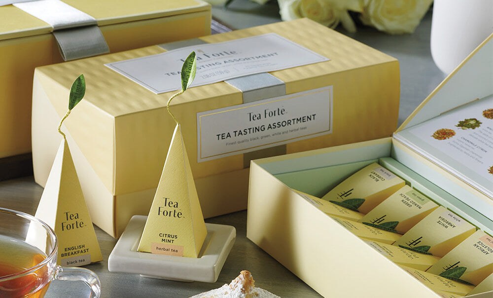 Tea Tasting Assortment in a 20 and 10 count presentation box on table with infusers, flowers and glass cups