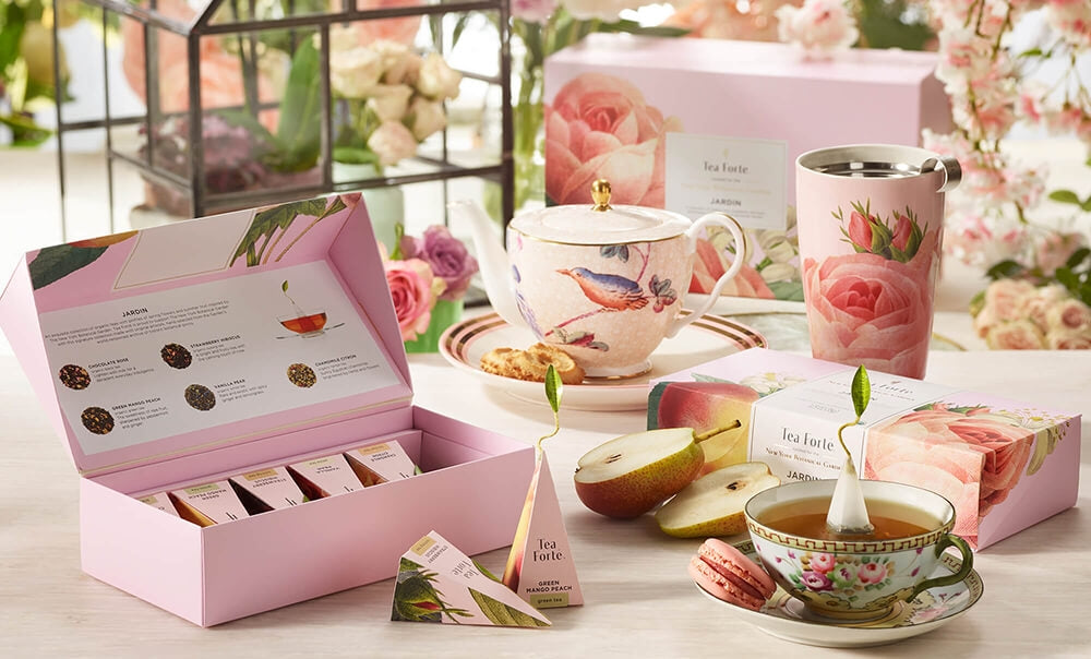 Jardin Collection on table with fresh fruit, teacup, teapot and flowers in the background