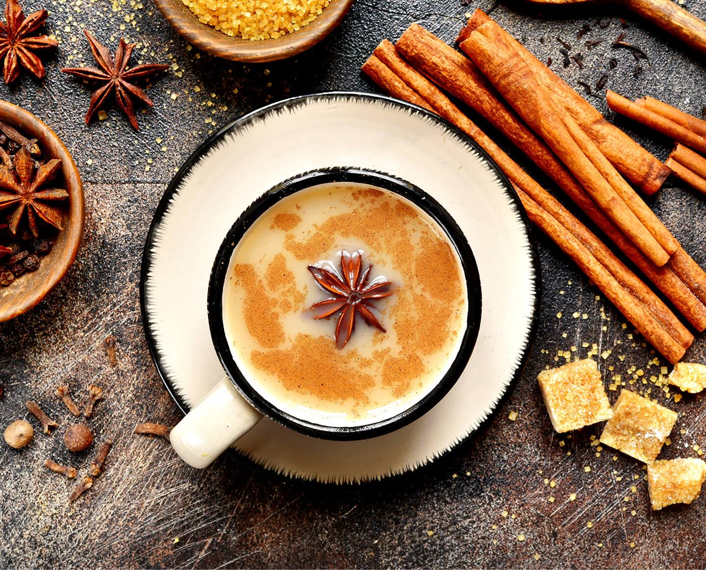 Chai Latte in a cup from above with cinnamon sticks and anise pods on the table.