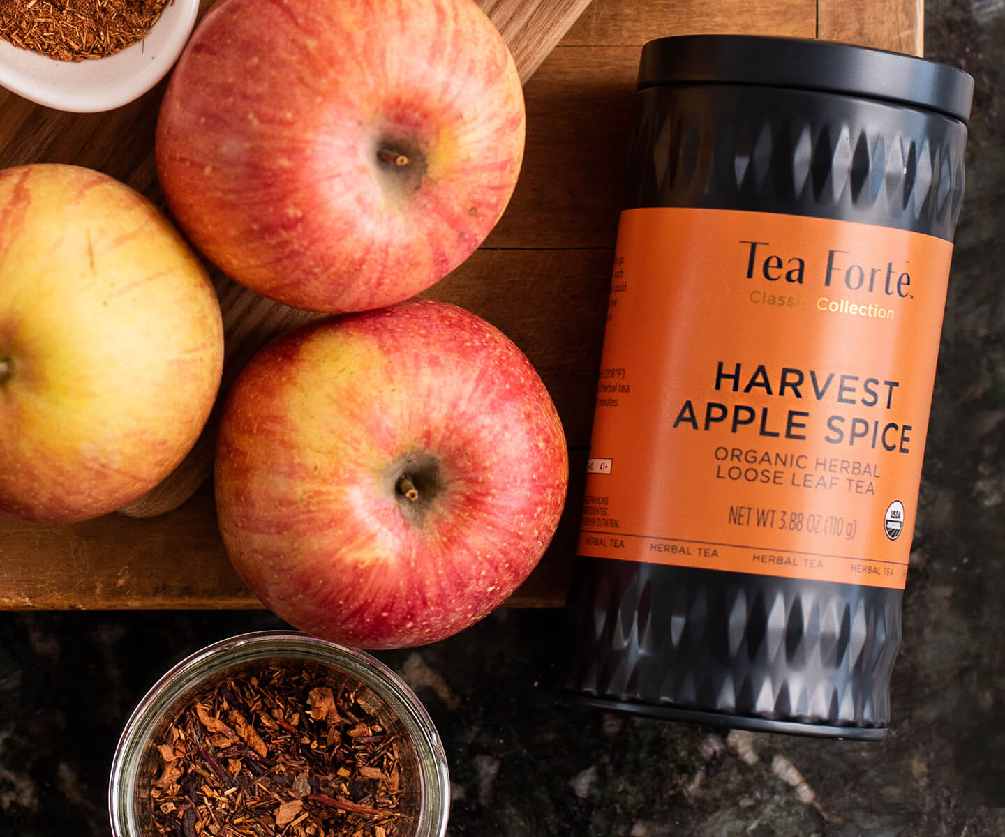 Harvest Apple Spice loose tea canister on a table with apples.