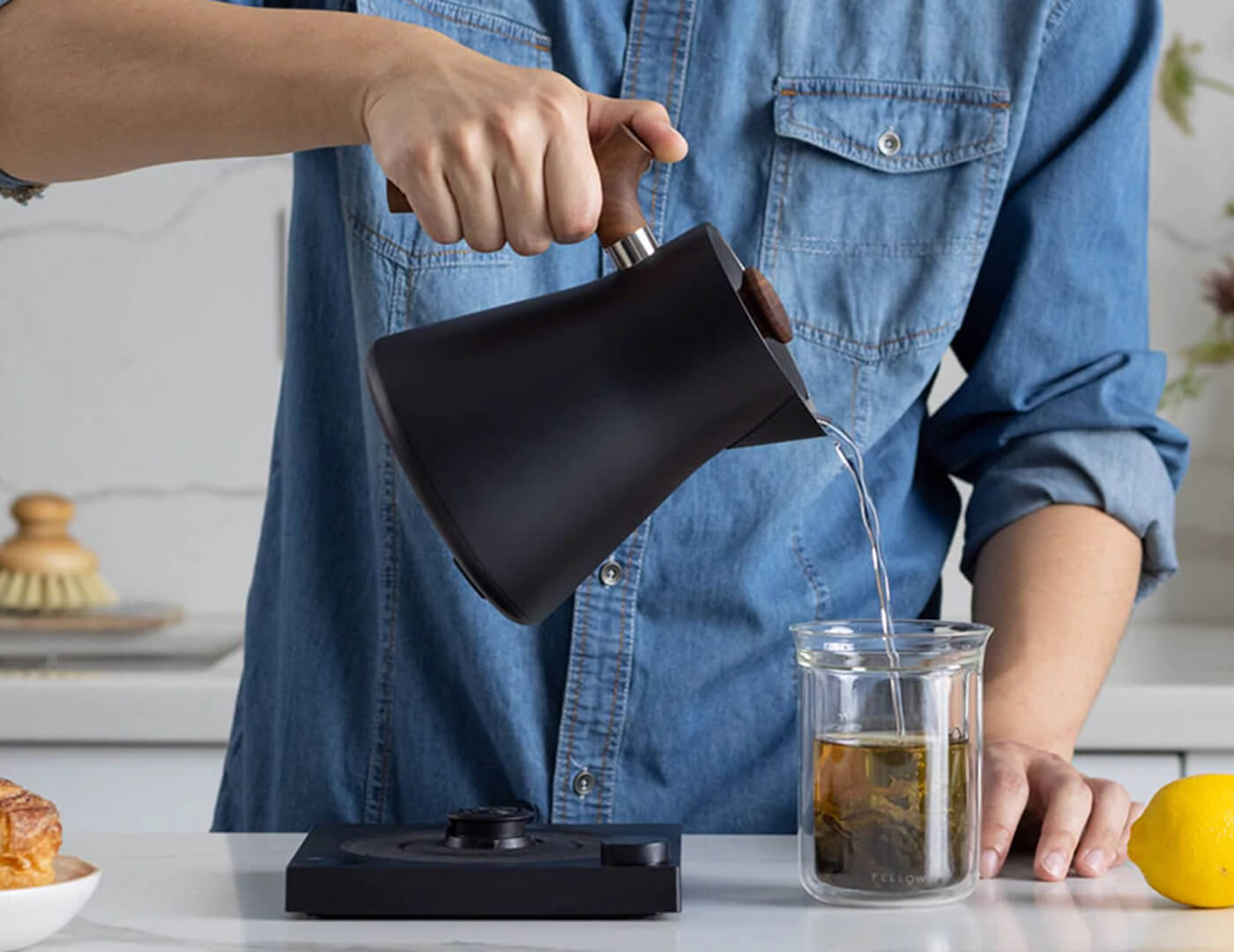 Pouring hot water into a tea glass from the Black Corvo Kettle EKG with Walnut handle