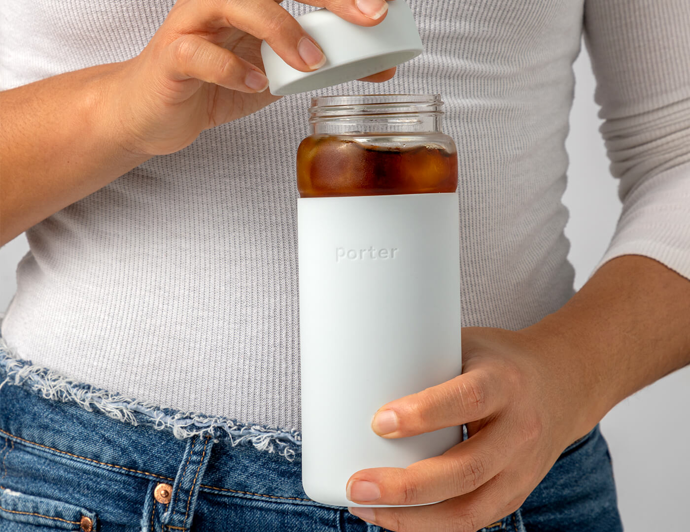 Woman holding Porter Water Bottle and removing the lid