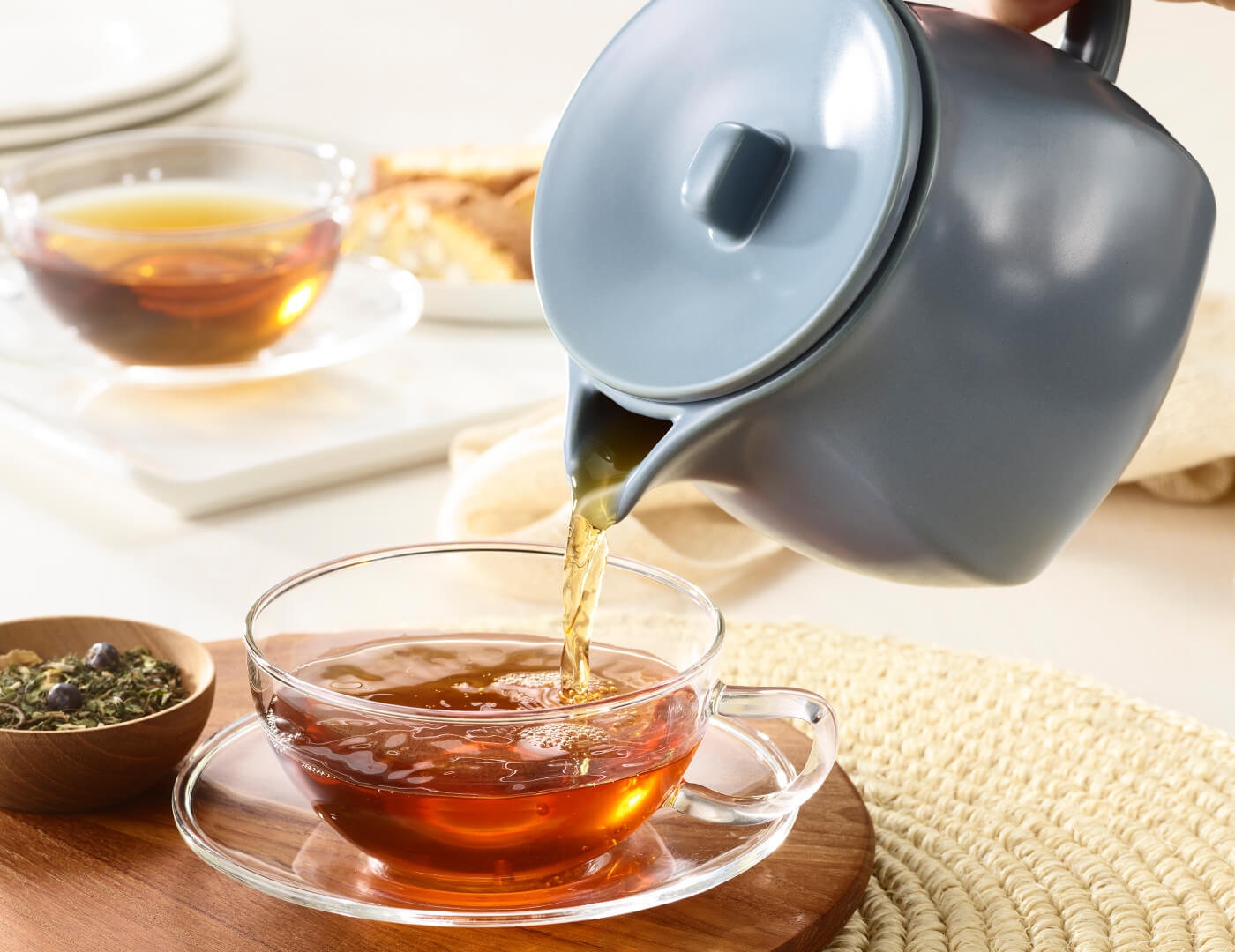 Fiore Stone Blue Teapot pouring steeped tea into a glass cup