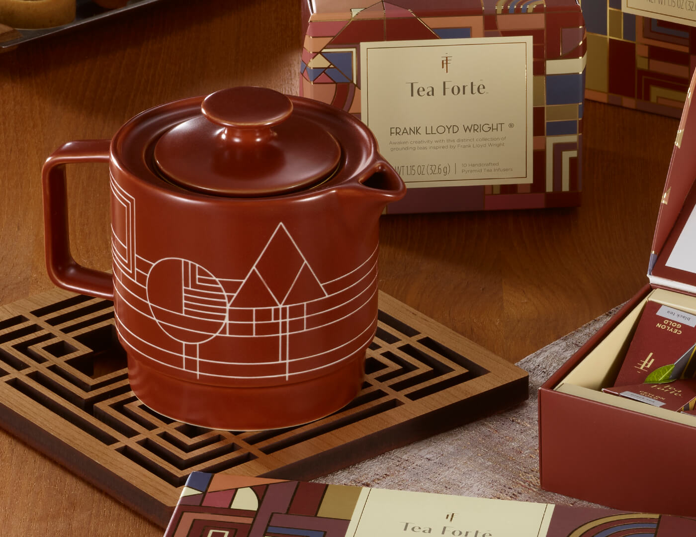 Terra stoneware teapot with lid on, on wooden table with other Frank Lloyd Wright tea items