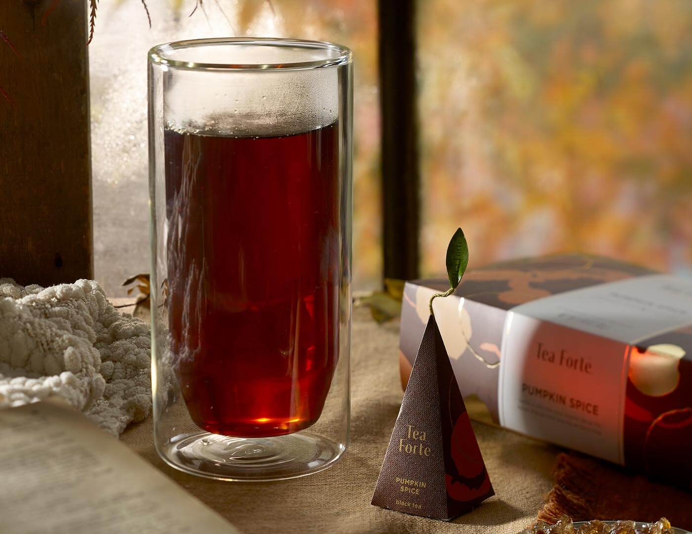 Pumpkin Spice tea in a tall glass with pyramid infuser on table