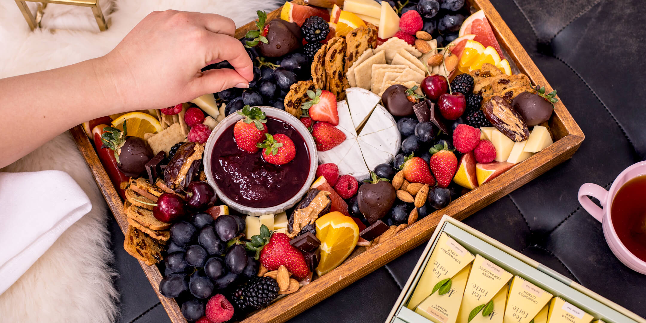 Dipping a strawberry into chocolate on a Charcuterie Board